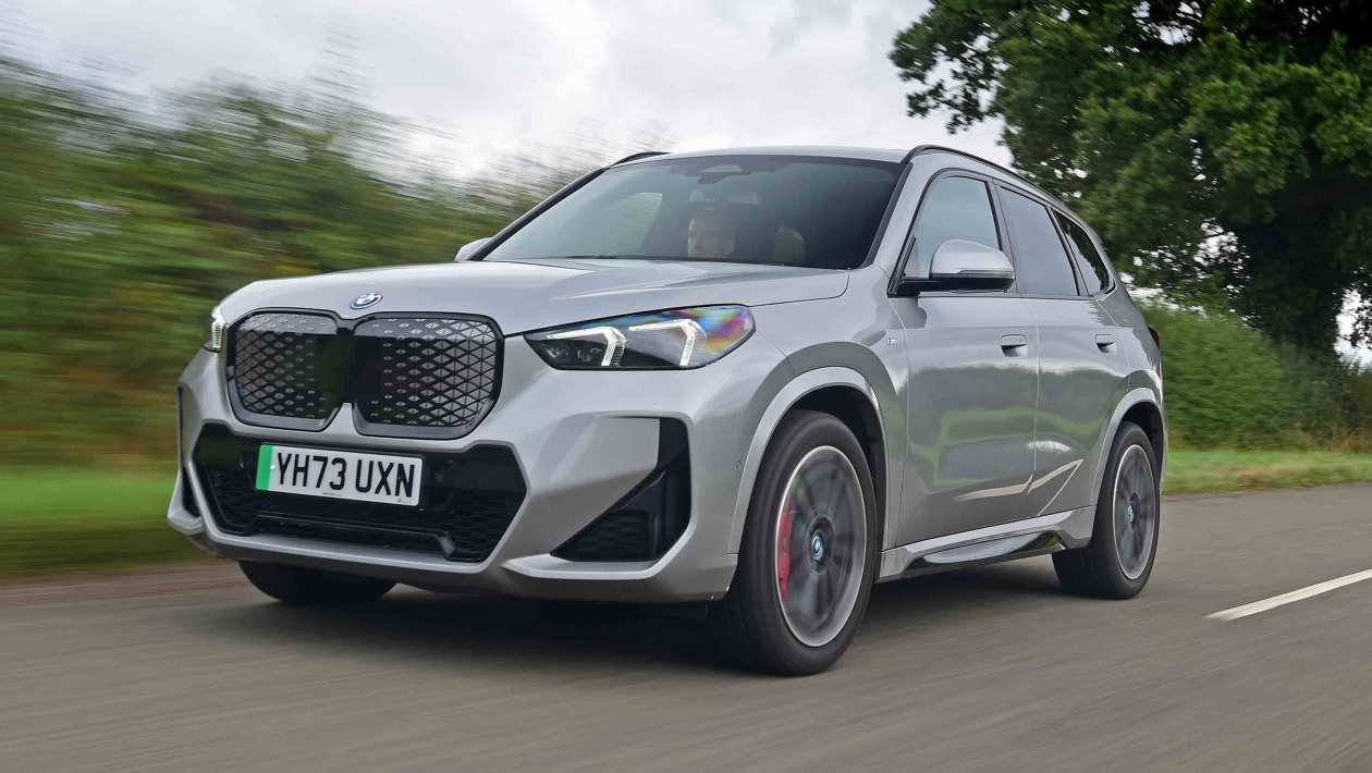 Auto Express news reporter Ellis Hyde holding two BMW iX1 undertrays